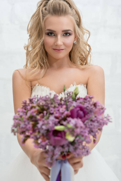 Young bride in studio with exquisite bouquet - Фото, зображення