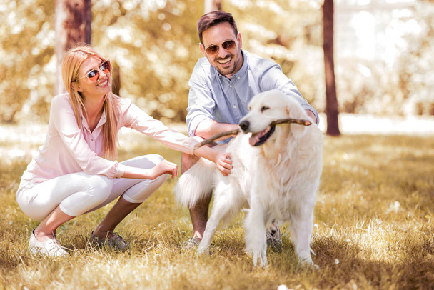glückliches junges Paar geht mit Hund in der Natur spazieren. - Foto, Bild