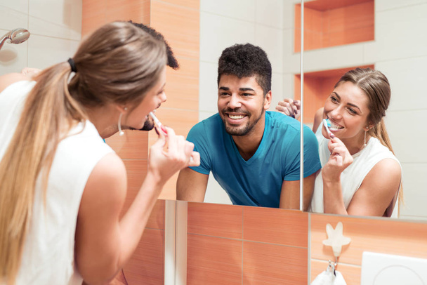 Woman brushing teeth in bathroom with boyfriend. - Valokuva, kuva
