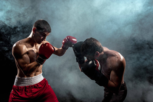 Two professional boxer boxing on black smoky background, - Фото, изображение
