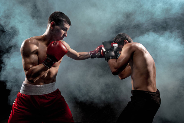Two professional boxer boxing on black smoky background, - Zdjęcie, obraz