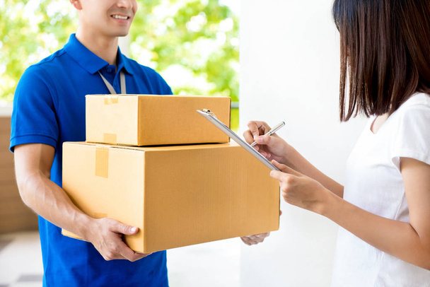 Woman signing document, receiving parcel box from delivery man  - Foto, Imagem