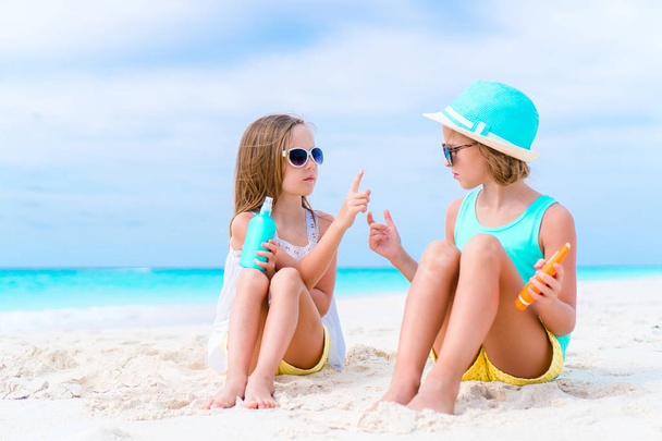 Crianças aplicando protetor solar umas às outras na praia. O conceito de proteção contra radiação ultravioleta
 - Foto, Imagem