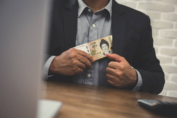 Zakenman brengen geld, Koreaanse won bankbiljetten, in zijn pak  - Foto, afbeelding