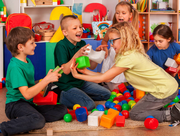 Los niños construyen bloques en el jardín de infantes. Grupo niños jugando juguete piso
 . - Foto, imagen