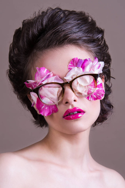 Fashion beauty model girl wearing stylish glasses full of rose petals. Creative makeup and hairstyle. - Zdjęcie, obraz