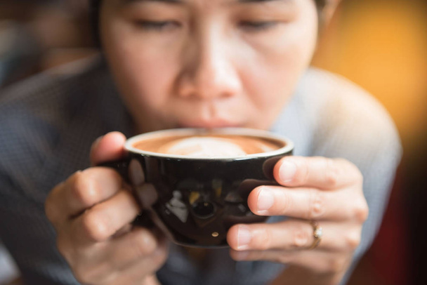 Le donne che tengono una tazza calda di caffè nelle mani in caffetteria al mattino
   - Foto, immagini