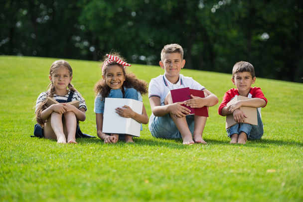 Children reading books in park - Foto, afbeelding