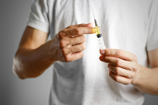 A young man holding a syringe with a needle with the drug. Shake - Photo, image