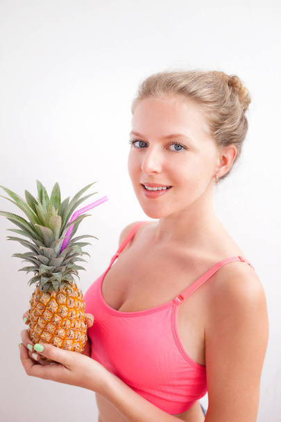 Portrait of a pretty young summer girl holding pineapple isolated over  background. Concept of a healthy lifestyle. - Fotó, kép