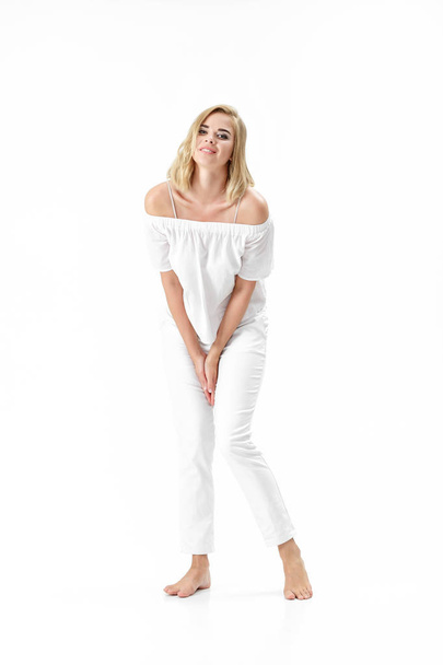 Beautiful smiling blond woman in white blouse and pants on white background - Фото, зображення