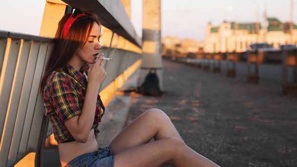  woman smokes on the bridge - 写真・画像