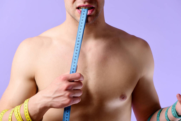 Weight management idea. Male holds blue measuring tape with teeth - Фото, изображение