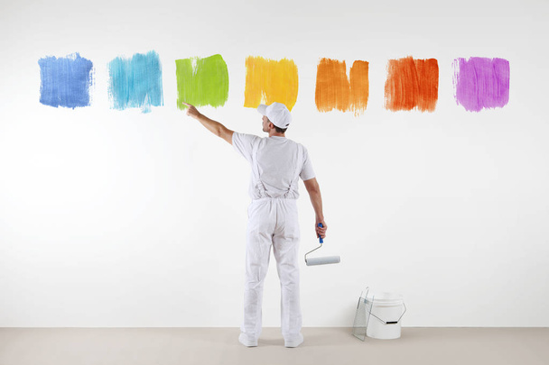Вид ззаду художника, який вказує пальцем на кольори на стіні
 - Фото, зображення