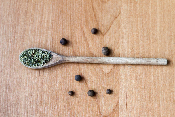 Composition of a wooden spoon with green spices and small black  - 写真・画像