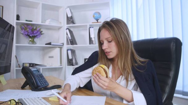 Busy woman talking on the phone while having burger - Foto, imagen
