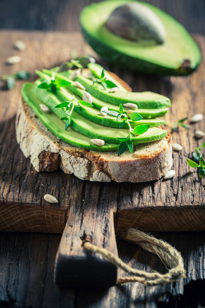 Sandwich with avocado, herbs and seeds on wooden table - Foto, Bild