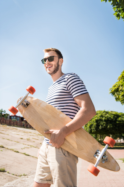Man holding skateboard - Foto, afbeelding