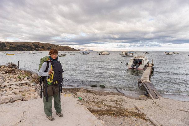 Una persona con mochila esperando el barco en el muelle de Copacabana en el lago Titicaca, uno de los destinos turísticos más pintorescos de Bolivia. Aventuras de viaje y vacaciones en las Américas
. - Foto, imagen