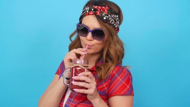 Beautiful young woman holding a red smoothie - Materiał filmowy, wideo