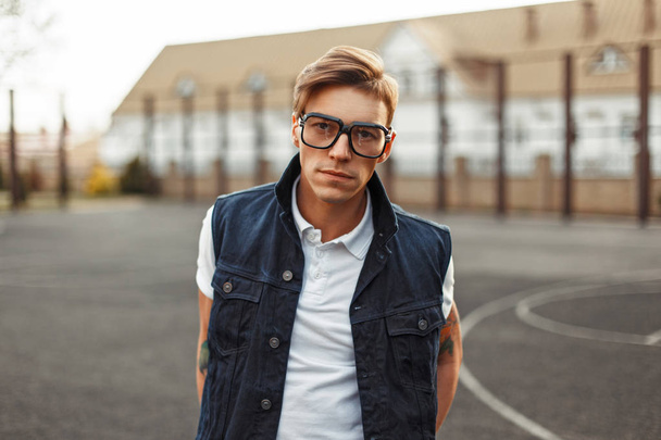 Stylish handsome man with glasses and a denim vest outdoors - Photo, Image