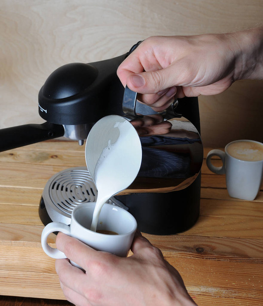 Barista man is making cappuccino. Pours milk closeup - Fotó, kép