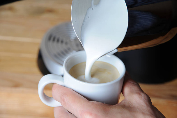 Barista man is making cappuccino. Pours milk closeup - Fotoğraf, Görsel