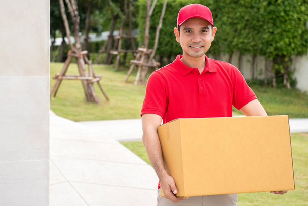 Delivery man in red uniform holding parcel box - Photo, Image