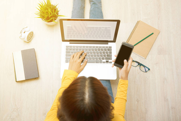 Draufsicht auf junge Frau, die mit Laptop auf dem Boden sitzt - Foto, Bild