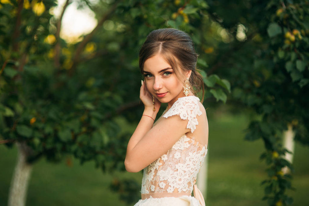 Young girl in wedding dress in park posing for photographer. portrait - Фото, изображение