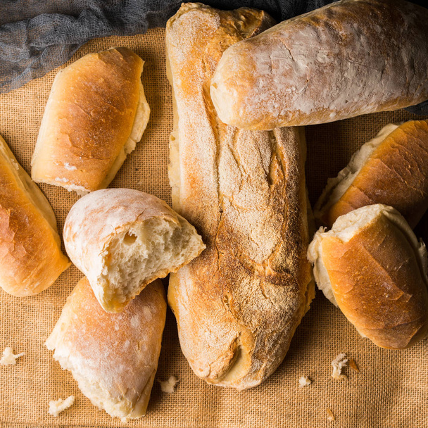 Freshly baked bread on burlap dark wooden background - Фото, изображение
