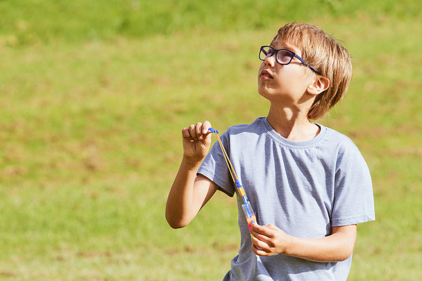 Child playing outdoors in a park with arrow helicopter elastic rocket toy - Photo, Image