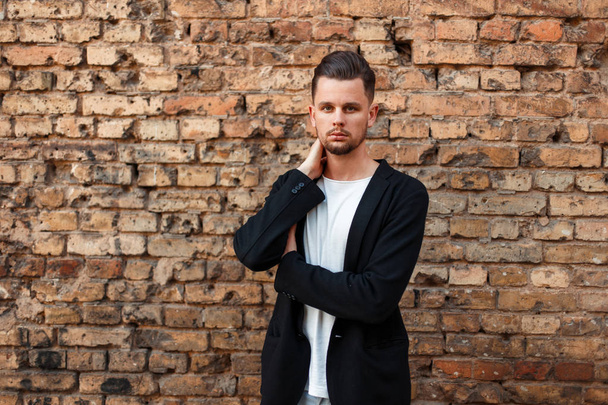 Handsome young man in stylish business clothes near a brick wall - Foto, Bild