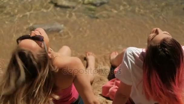 Twee vrouwen zittend op strand in warm weer. - Video