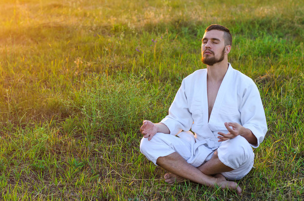 A man who wields martial arts sits in a lotus pose, a copy of sp - Foto, Imagen