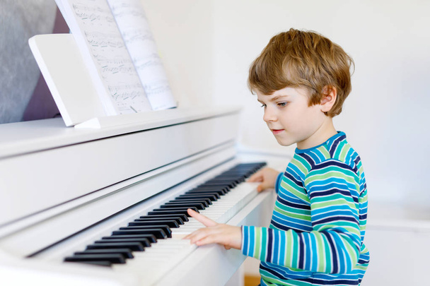 Szép kis gyerek fiú nappaliban vagy a Zeneiskolában zongorázni - Fotó, kép