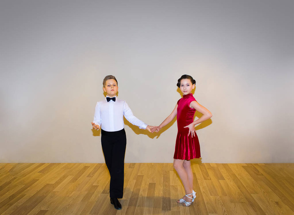 der junge Junge und das Mädchen posieren im Tanzstudio auf grau. das Konzept des Standardtanzes - Foto, Bild