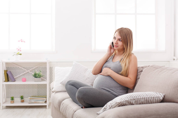 Hymyilevä raskaana oleva nainen puhuu älypuhelimellaan
 - Valokuva, kuva