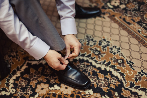 The man wears shoes. Tie the laces on the shoes. Men's style. Professions. To prepare for work, to the meeting. - Photo, Image