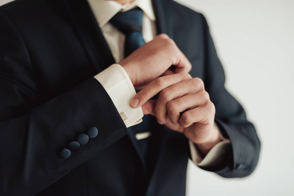 Elegant groom in wedding jacket wearing white shirt and turquoise tie. Groom's hands on blue suit. - Foto, Imagen