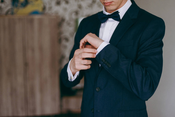 Elegant groom in wedding jacket wearing white shirt and turquoise tie. Groom's hands on blue suit. - Photo, Image