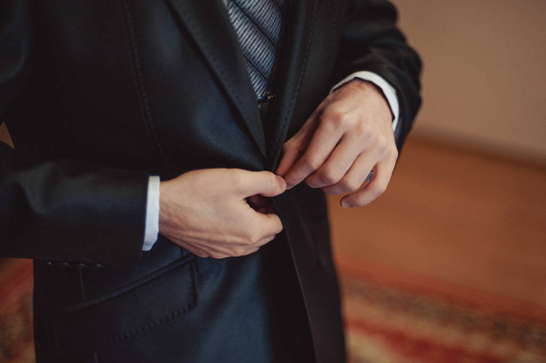 Elegant groom in wedding jacket wearing white shirt and turquoise tie. Groom's hands on blue suit. - Фото, зображення