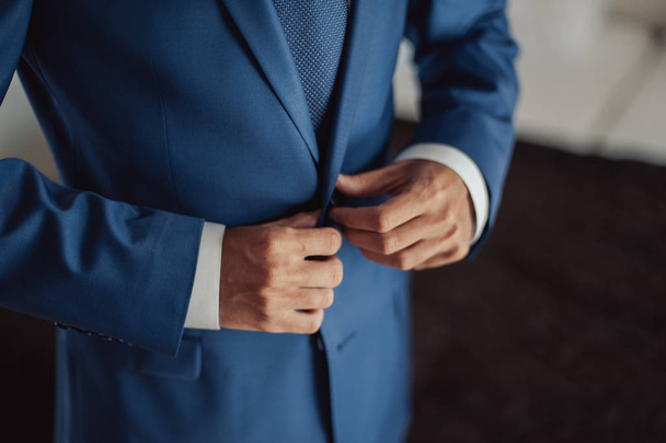 Élégant marié vêtu d'une chemise blanche et d'une cravate turquoise. Les mains de Groom sur costume bleu
. - Photo, image
