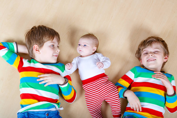 Двоє щасливих маленьких дошкільнят хлопчиків з новонародженою дівчинкою
 - Фото, зображення