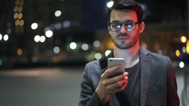 Young businessman walking in a night street and web surfing close up - Footage, Video