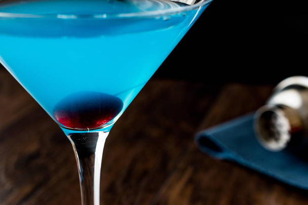 Blue Moon Cocktail with cherry on wooden surface. - Photo, Image
