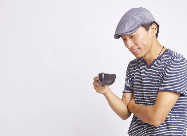 asiatische Mann lächelt auf Tasse Kaffee isoliert auf weiß - Foto, Bild