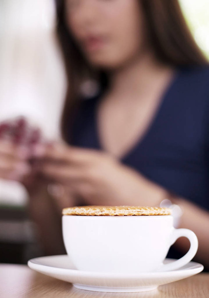 stroopvohveli kuumalla kahvikupilla ja hämärä nainen
 - Valokuva, kuva