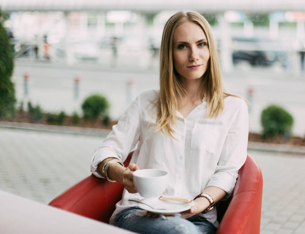Beautiful young woman holding the cup of tea in the cafe. - Foto, Bild