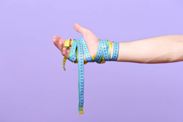 Mans wrist wrapped with cyan and yellow measuring tapes - Foto, Imagem